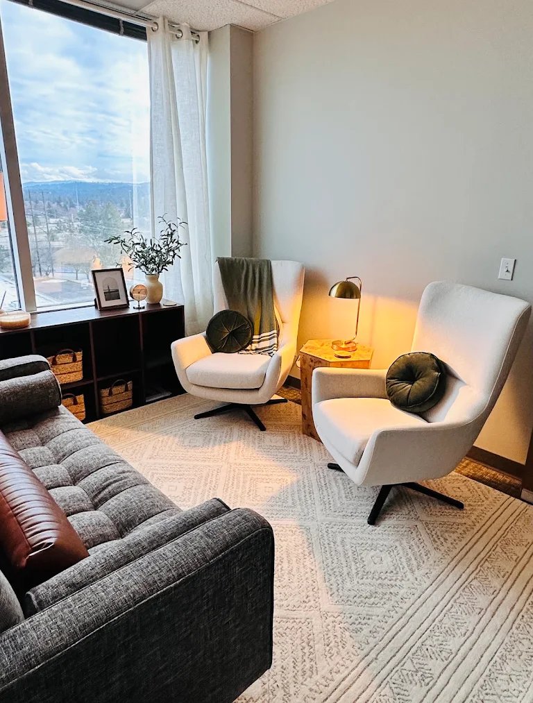 Kathryn's counseling office: cream swivel chairs, a gray tufted sofa and a window overlooking the Spokane hills